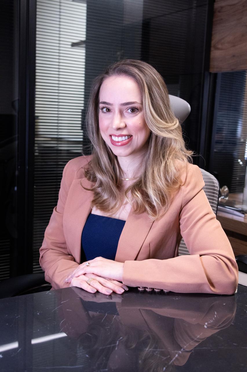 Dra. Bárbara Silveira, ginecologista, sentada em seu consultório